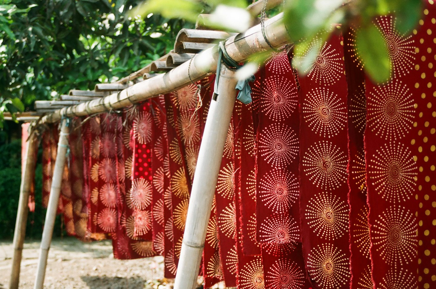 Patterned fabric strips hang from a rustic bamboo drying rack.